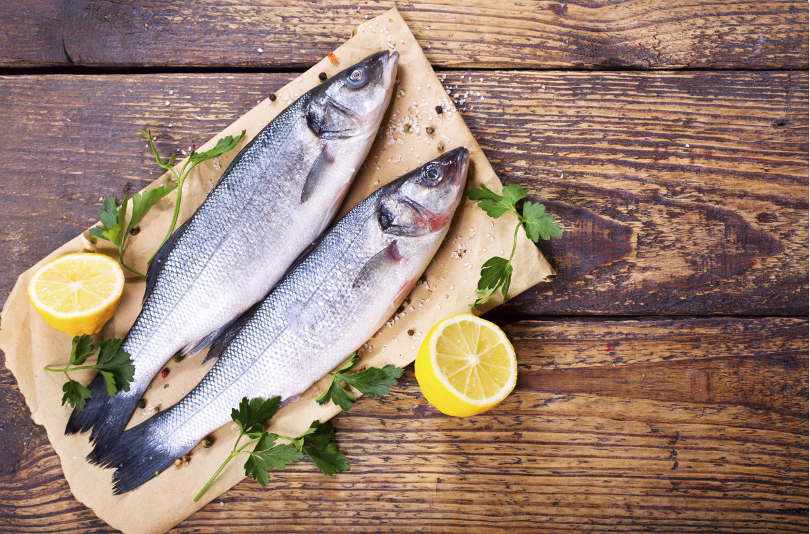 Fresh whole fish with lemon and parsley on rustic wooden table | Taylor Gleason Enterprises